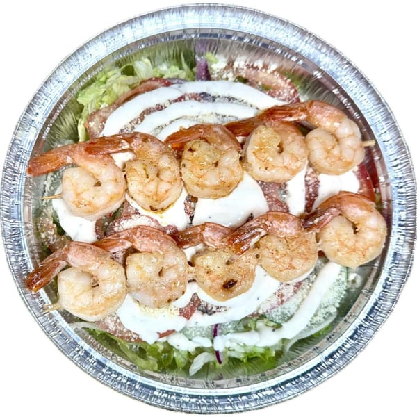 Halal shrimp skewers with white sauce and lettuce in a foil takeout container.