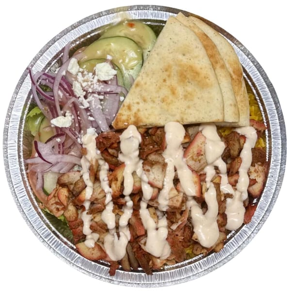 Halal chicken over rice with pita bread, cucumber, red onions, and feta cheese in a foil container.