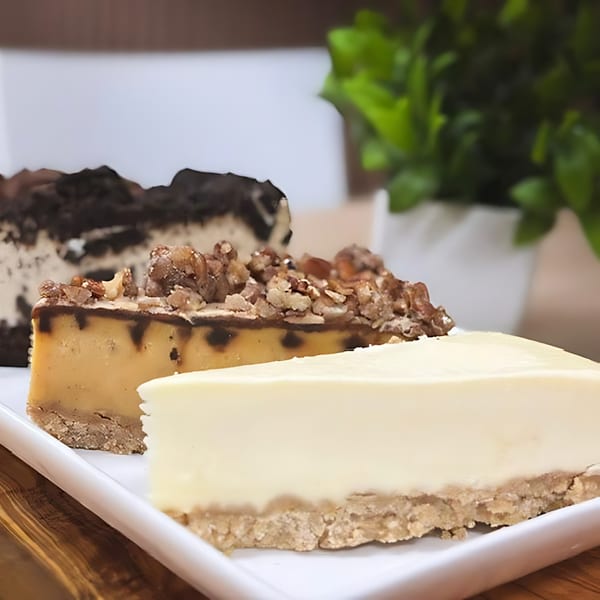 Three slices of cheesecake, including plain, caramel pecan, and chocolate, on a white platter.